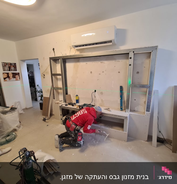 עובד מתקין לוחות גבס על קיר עם מסגרת מתכת